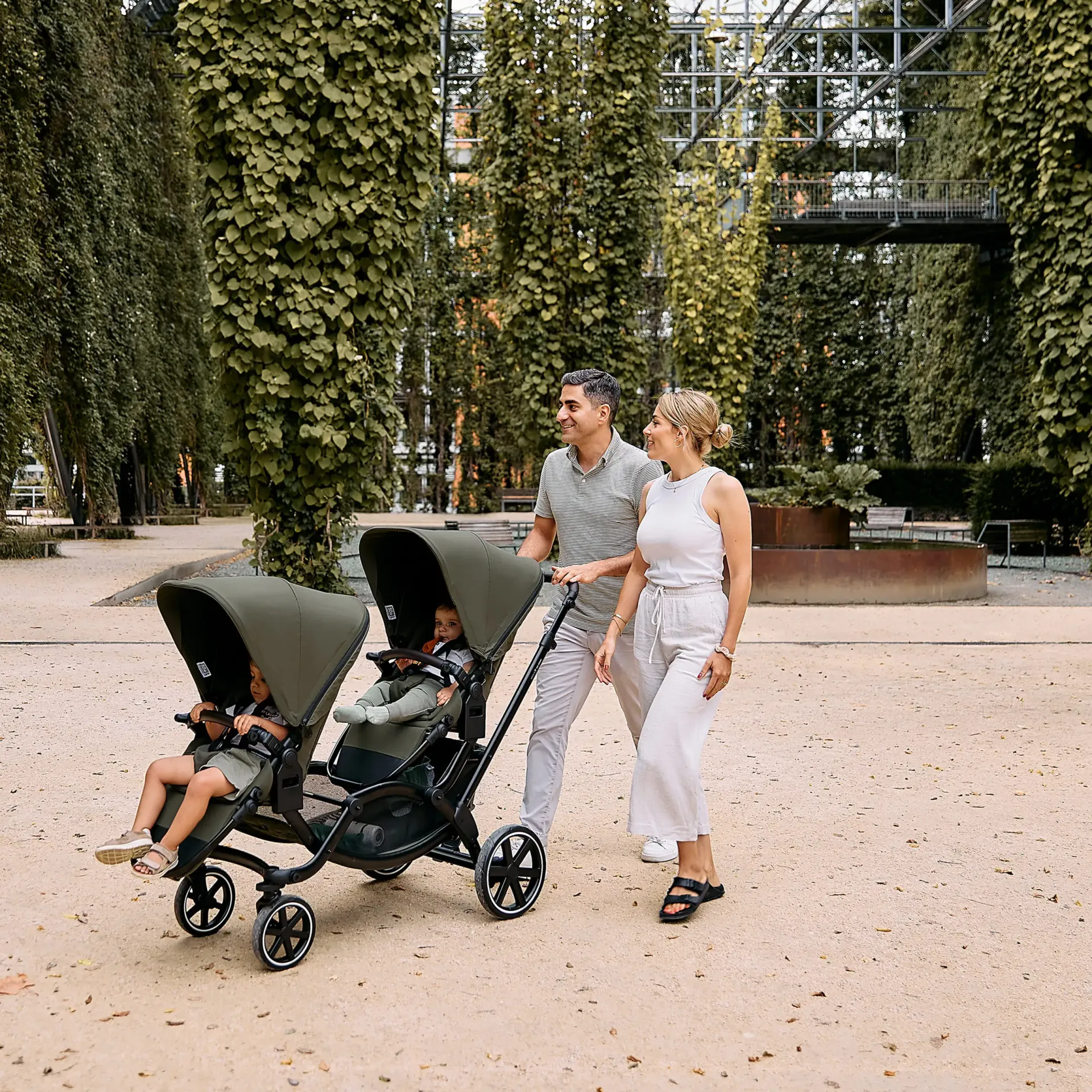 familie geht mit geschwisterwagen spazieren familie geht mit geschwisterwagen spazieren