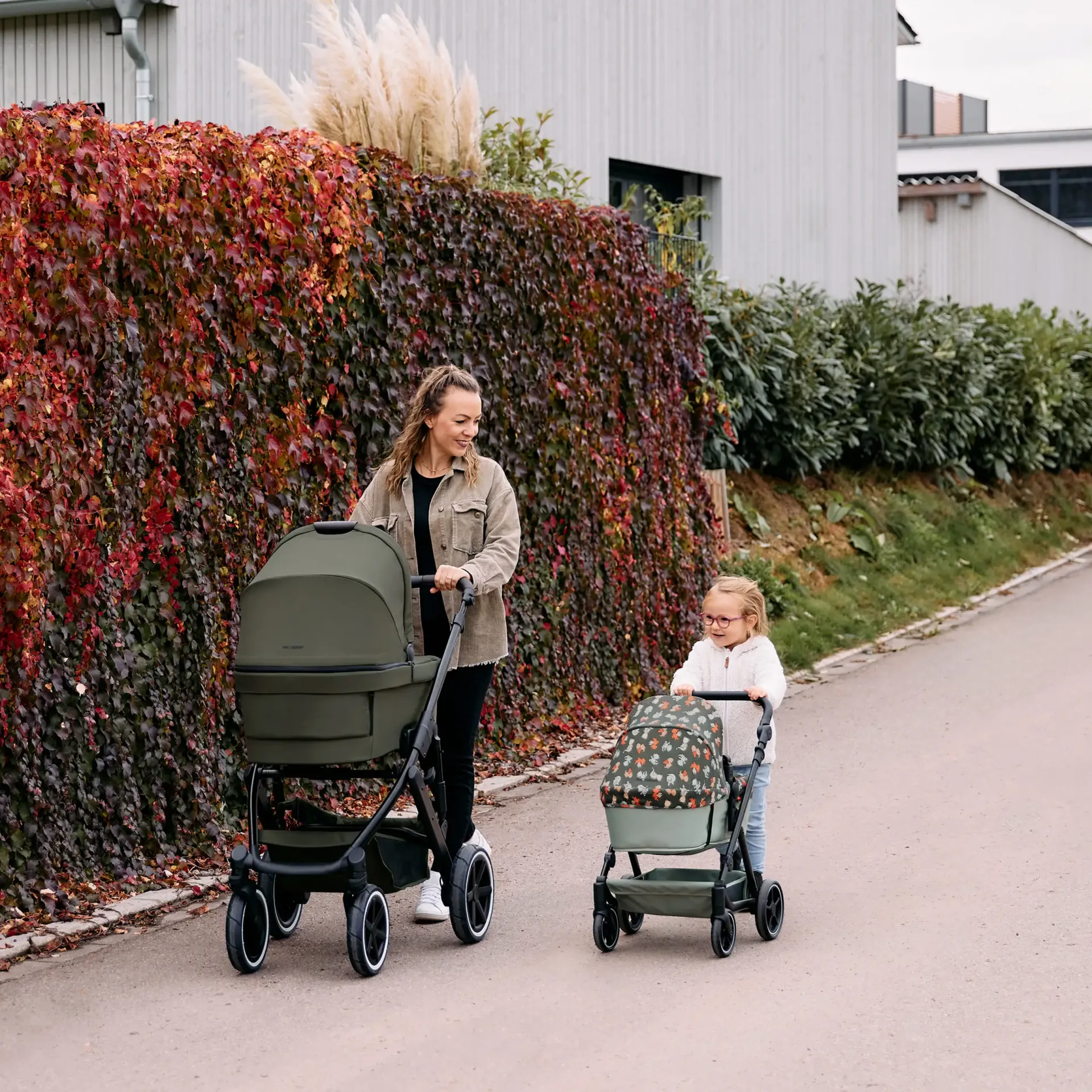 mutter schiebt kinderwagen und kind schiebt den puppenwagen mutter schiebt kinderwagen und kind schiebt den puppenwagen